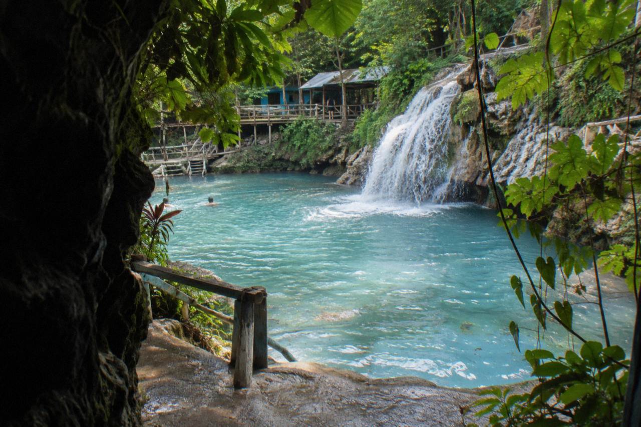 Turquoise waterfall pool surrounded by dense green jungle foliage near Ocho Rios