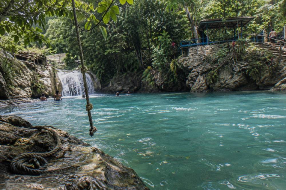 Rope swing hanging over a turquoise pool at Island Gully Falls