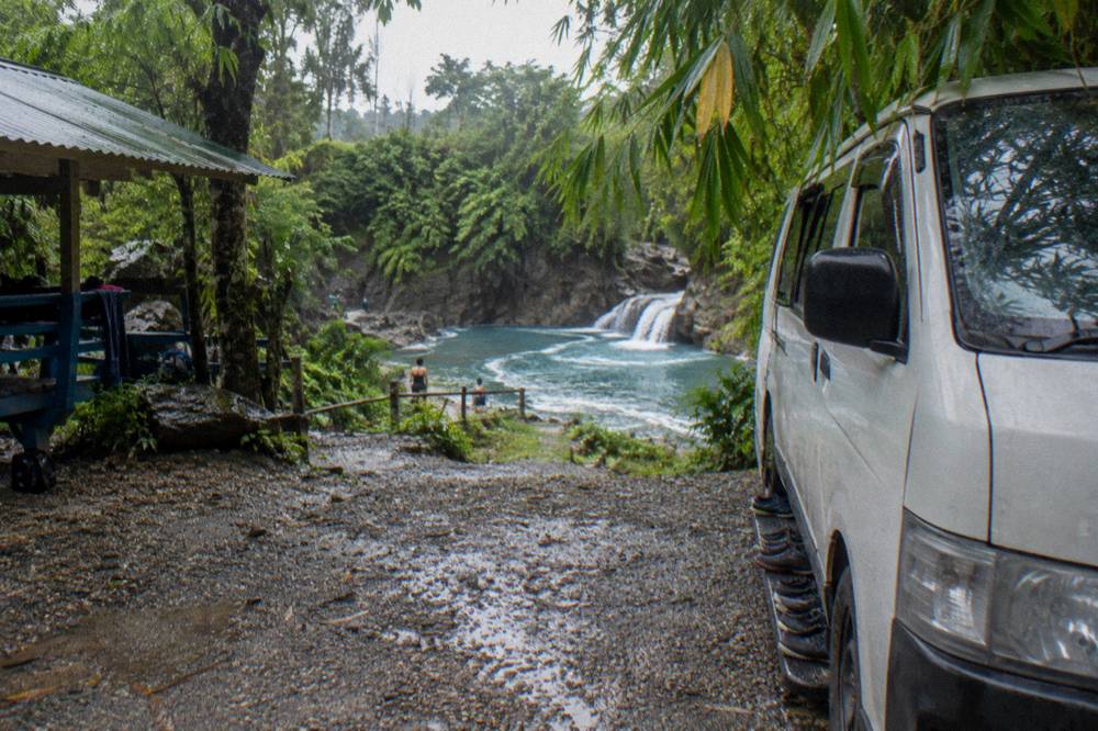 Small tour van parked on a gravel road near the falls entrance