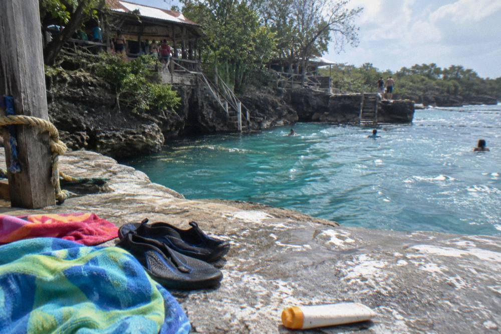 Water shoes and towels drying on a rock ledge beside the pools