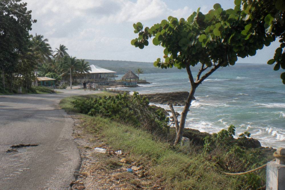 Coastal road curving along green hillsides above the Caribbean sea