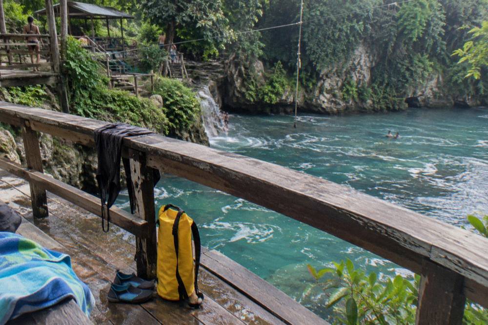 Water shoes, towels and a dry bag arranged on a wooden bench