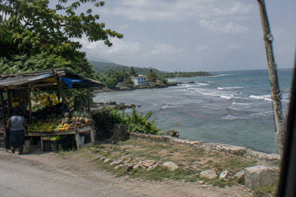 Winding coastal road with green hillsides seen from a vehicle window in Jamaica