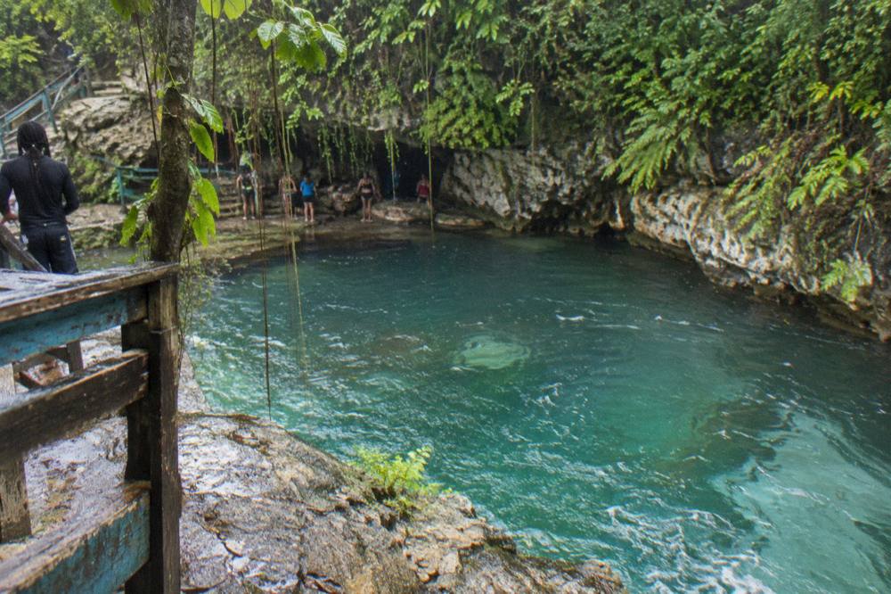 Small group of visitors gathered with a guide beside a jungle waterfall pool