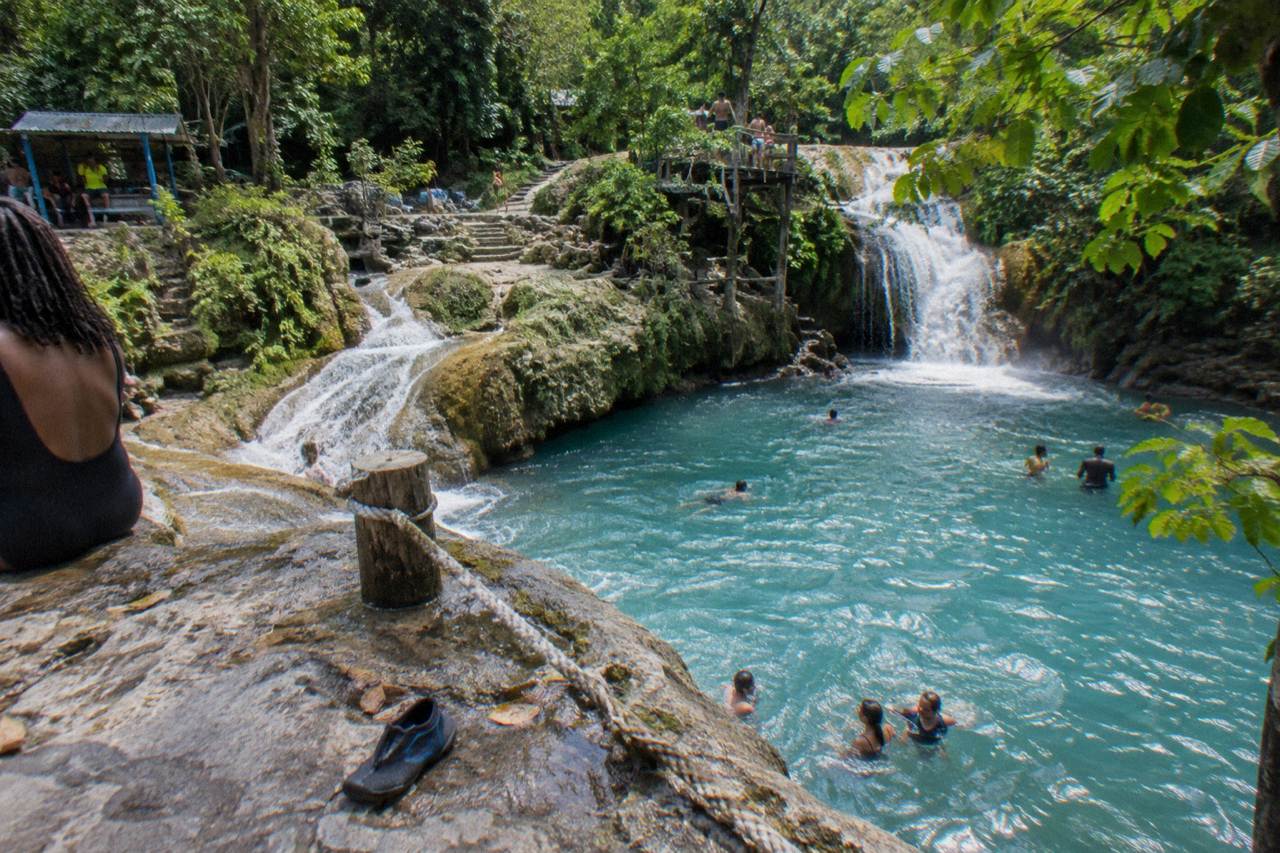 Turquoise waterfall pool surrounded by dense jungle foliage in the hills above Ocho Rios