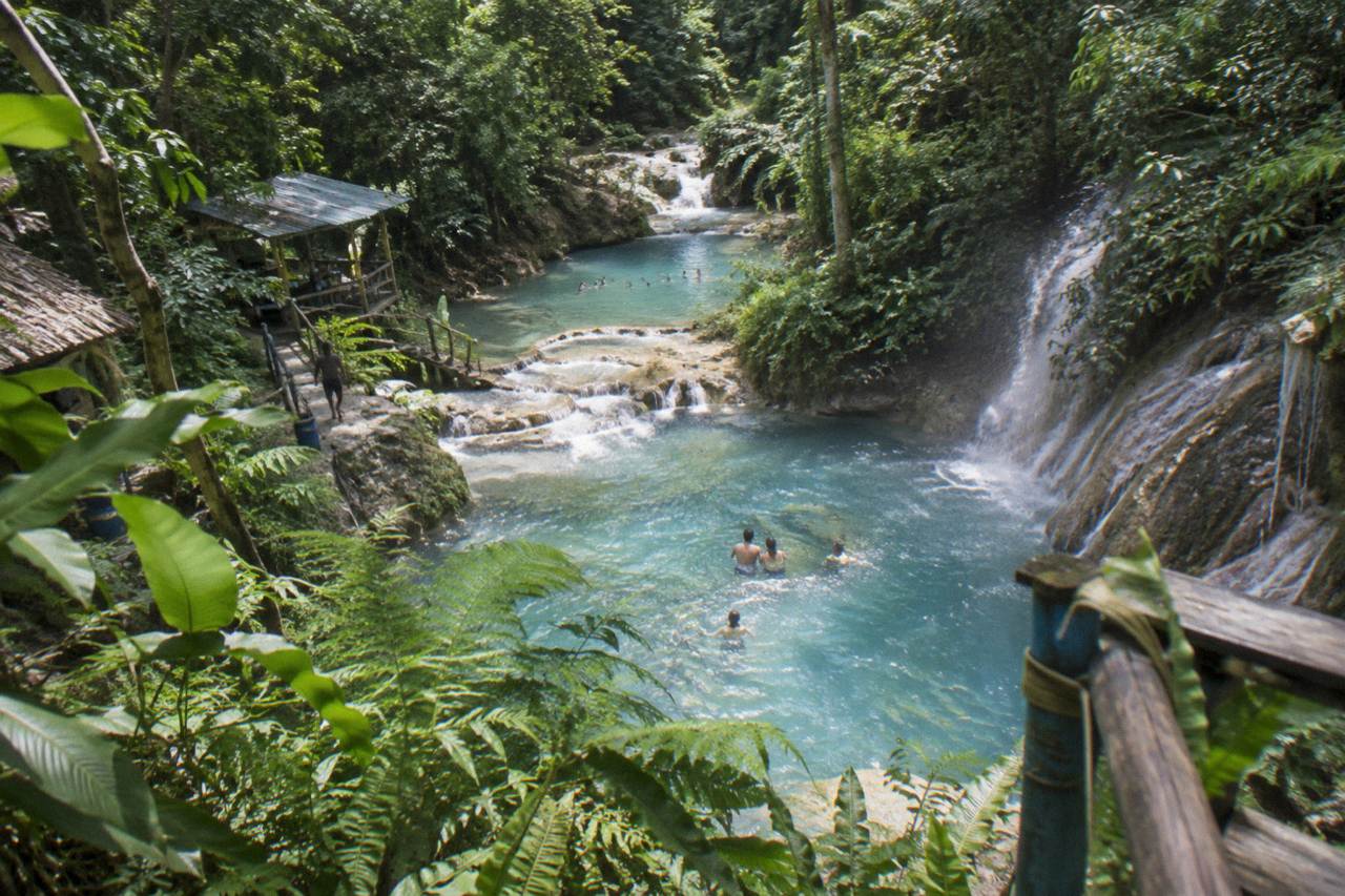 Turquoise waterfall pools surrounded by dense green forest in the hills above Ocho Rios