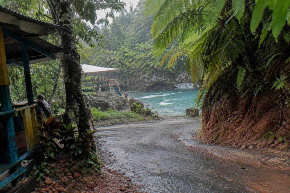Empty winding country road through green hills on the drive to a jungle waterfall