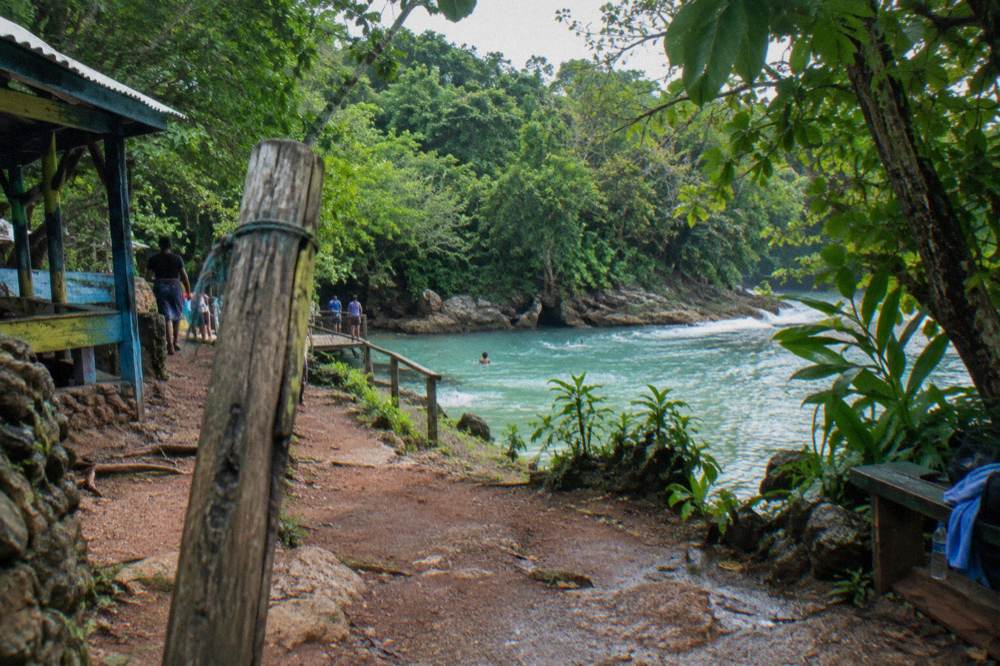 Wooden sign and entrance path at a jungle waterfall attraction in Saint Ann