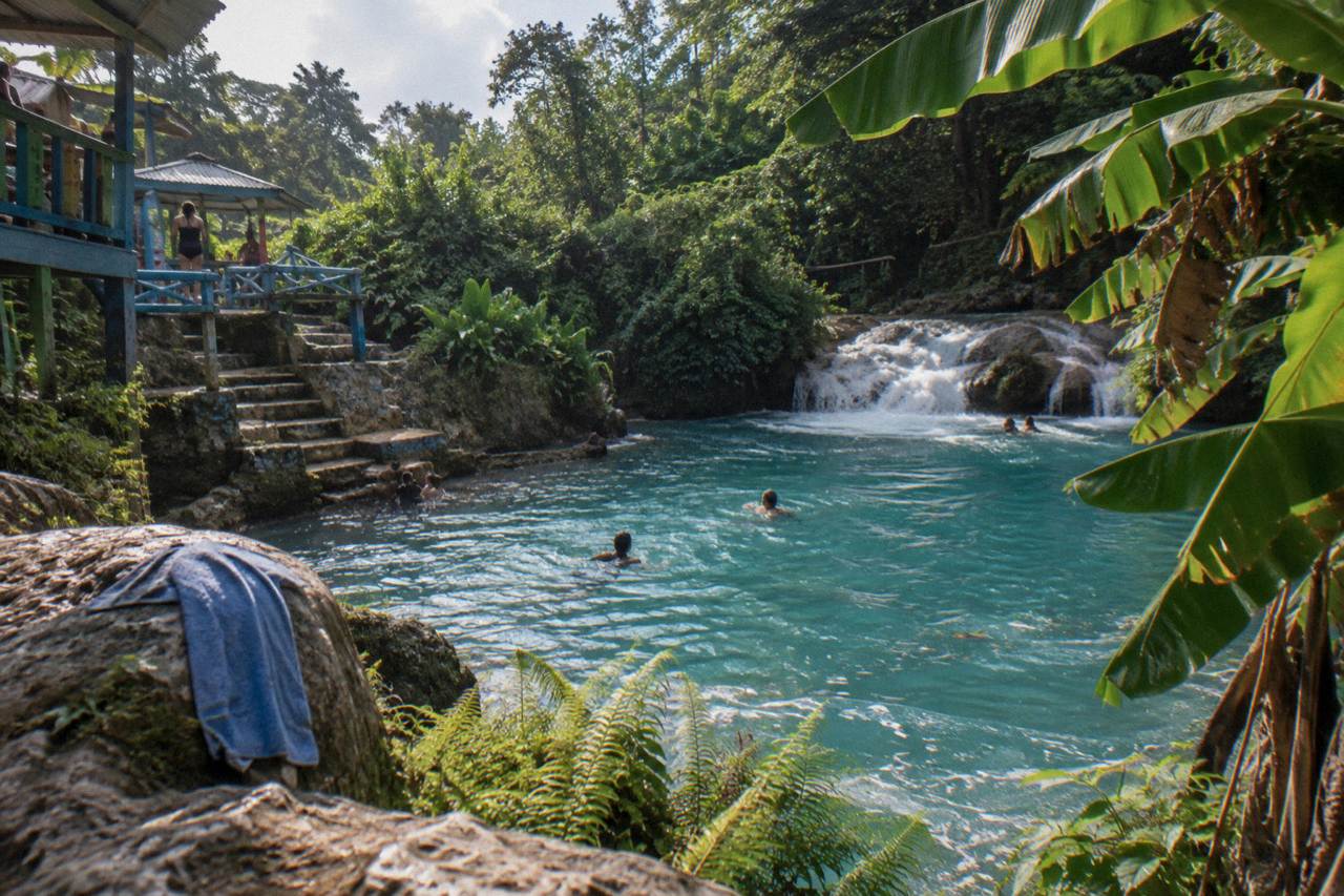Turquoise waterfall pool surrounded by lush green forest near Ocho Rios