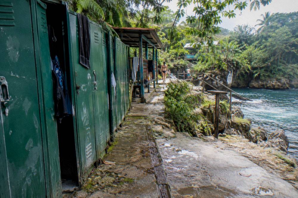 Wooden lockers and changing room doors along a path near a waterfall entrance