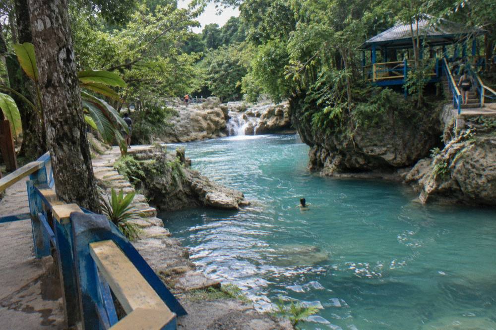 Limestone rocks and a small waterfall above a turquoise jungle river pool