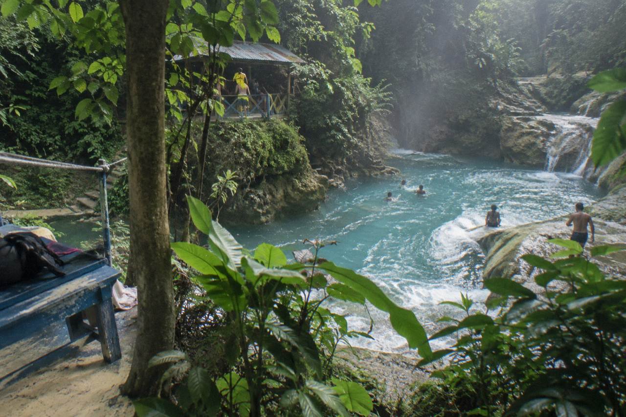 Turquoise waterfall pool surrounded by dense green forest in the hills above Ocho Rios